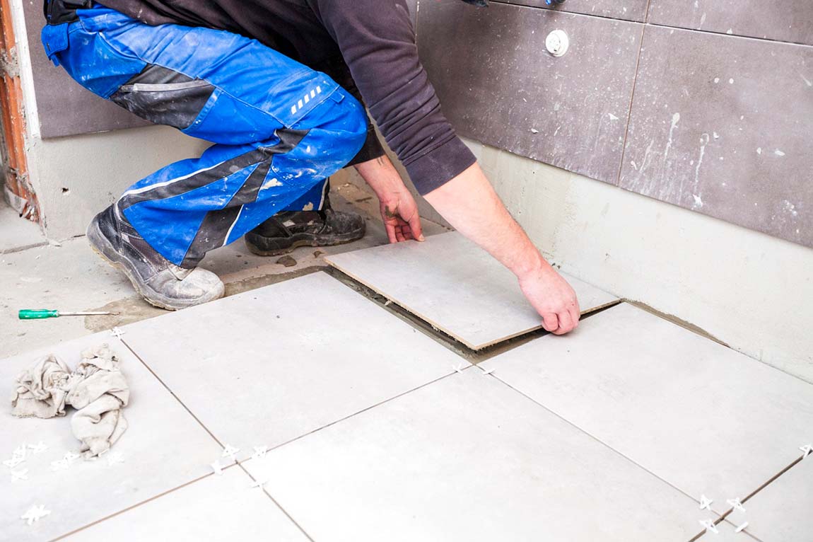 Before: contractor measuring existing beige tile bathroom before remodel in Barton Creek Austin